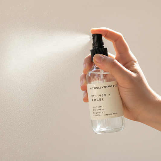 Hand misting a Catskills Vintage & Co. Vetiver + Amber room spray bottle
